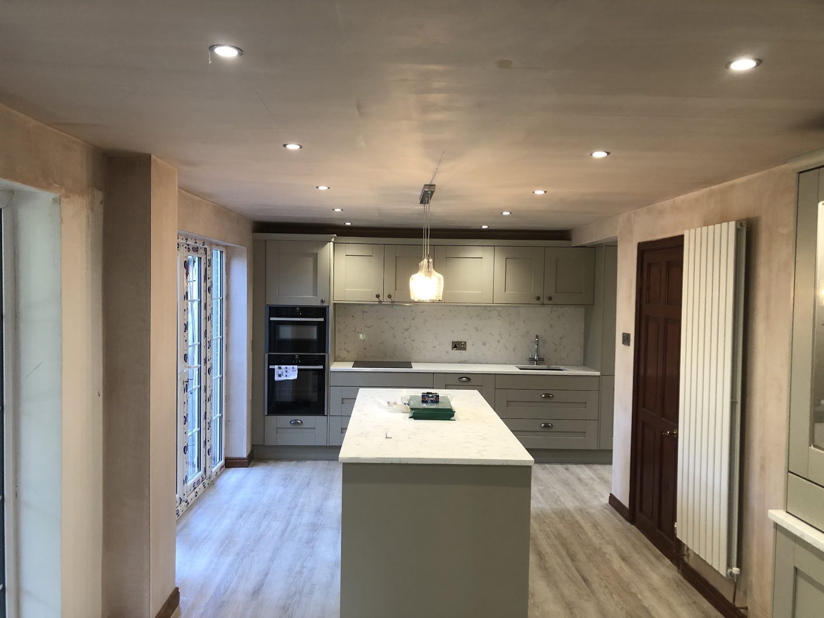 An open-plan kitchen with an island, downlights and a pendant light