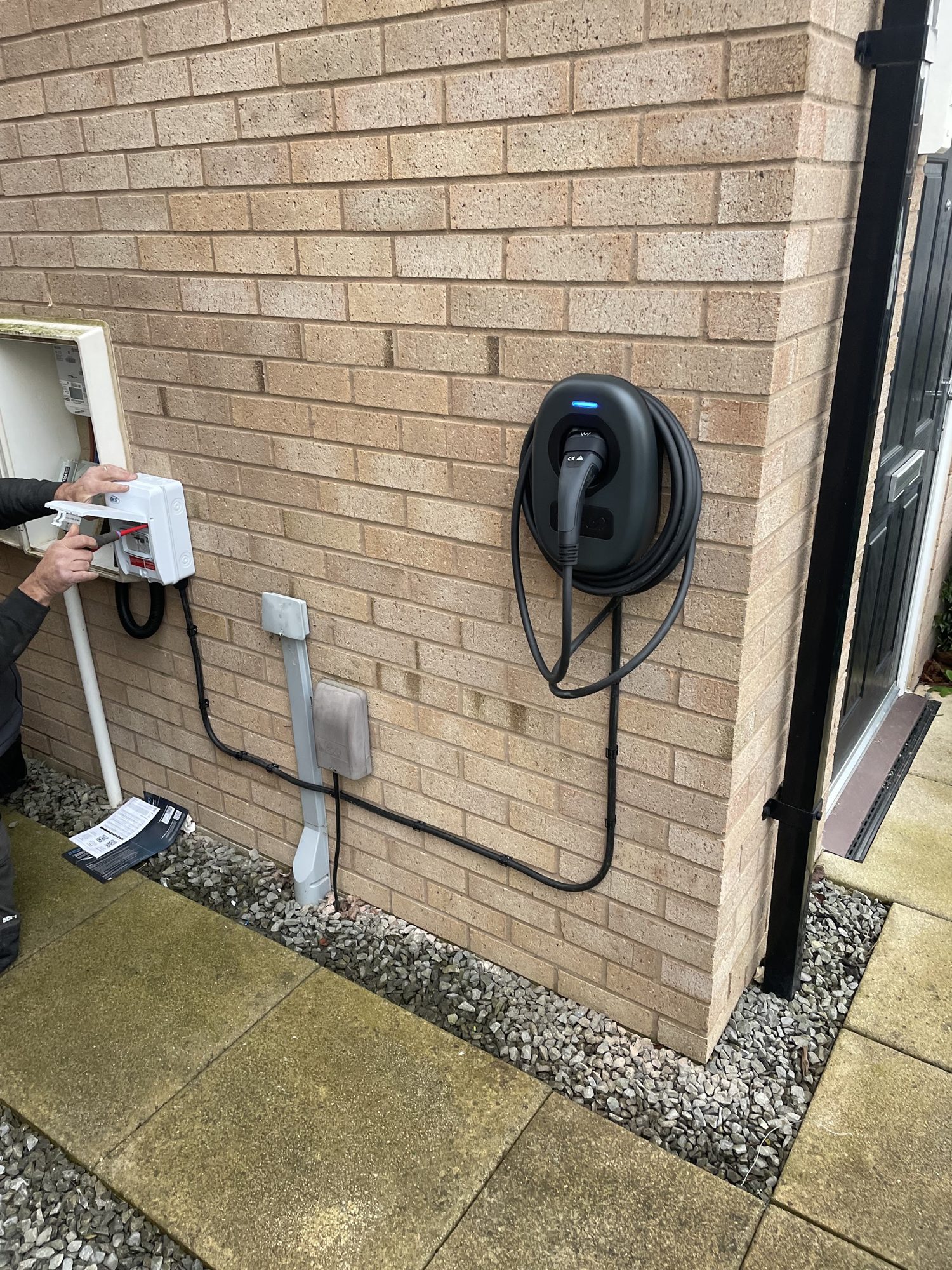 An EV charger and isolator fitted to a brick wall with the cable neatly run