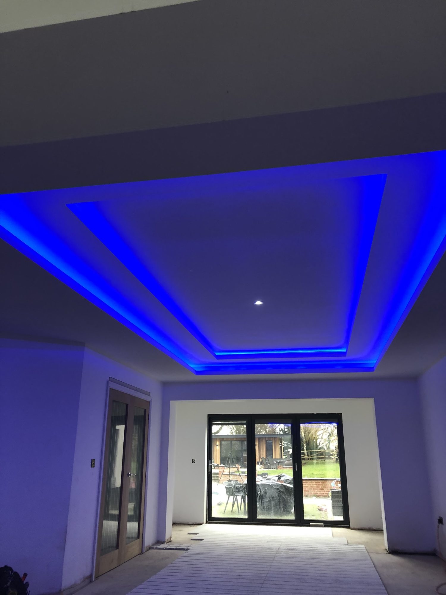 A ceiling with blue LED cove lighting looking out to patio doors